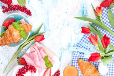 Ayçöreği ve pastırmalı tatlı bahar kahvaltısı. Bir buket kırmızı lale ve taze çilek ve kuşüzümü. Tatil kutlaması konsepti