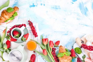 Ayçöreği ve pastırmalı tatlı bahar kahvaltısı. Bir buket kırmızı lale ve taze çilek ve kuşüzümü. Tatil kutlaması konsepti