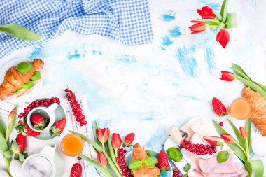 Ayçöreği ve pastırmalı tatlı bahar kahvaltısı. Bir buket kırmızı lale ve taze çilek ve kuşüzümü. Tatil kutlaması konsepti
