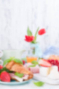 Ayçöreği ve pastırmalı tatlı bahar kahvaltısı. Bir buket kırmızı lale, çilek ve kuşüzümü. Tatil kutlaması konsepti. Bulanık arkaplan.