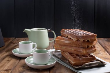 Tahta bir masada iki kupa çay ve çaydanlık. Taze ev yapımı waffle. Geleneksel kahvaltı. Metin için boş alan