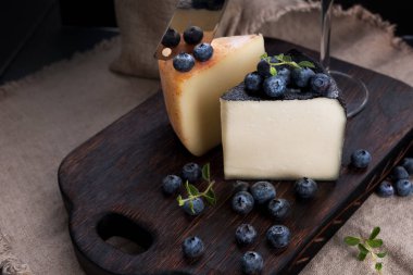 Beyaz pekorino peyniri ve yabanmersini. Geleneksel İtalyan sert peyniri özel akşam yemeği. Ahşap arka plan ve koyu renkli fotoğraf. Tipik sardunya peyniri.