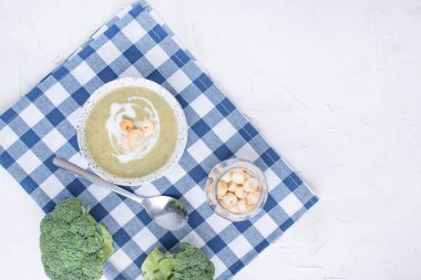 Brokoli, krema ve kraker ile krem çorba püresi. Sebze hafif bir arka plan üzerinde öğle yemeği. Plaka ve masanın üzerine peçete.