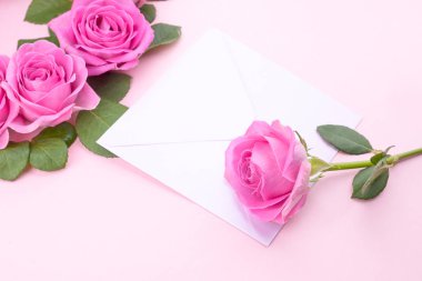 Gül ve zarf hafif arkaplanda. Buket ve mektup Sevgililer Günü ve Kadınlar Günü konseptinde hediye olarak. Metin için boş alan