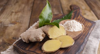 Tahta arka planda yaprakları olan taze zencefil. Sağlığa iyi gelir.