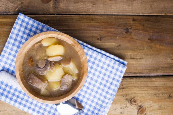 Sopa con salchichas y patatas sobre un fondo de madera en un tazón —  Fotos de Stock