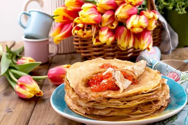 Pancakes with caviar and butter, a bouquet of fresh tulips and a — Stock Photo, Image