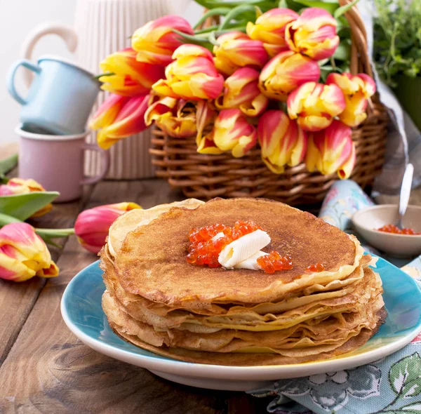 Pancakes with caviar and butter, a bouquet of fresh tulips and a — Stock Photo, Image