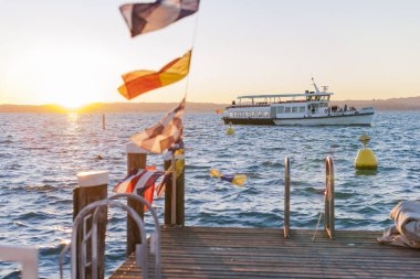 Gölde ya da denizde kırmızı-sarı güneşli bir gün batımı. Gökyüzü, kıyı, güneş ve