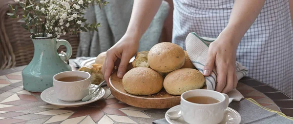 Bollos de hamburguesa caseros con albahaca en la mano de una mujer. Mesa servida —  Fotos de Stock