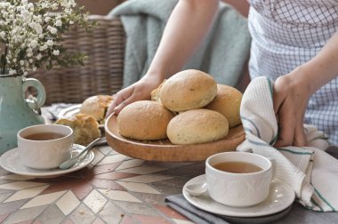Bir kadının elinde fesleğenli ev yapımı hamburger çörekleri. Servis Tablosu 