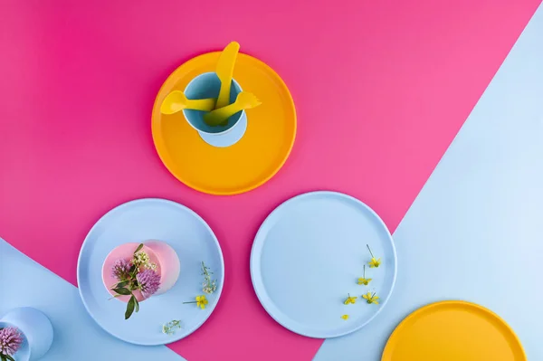 Multi-colored plastic picnic utensils on a pink background. Glas — Stock Photo, Image