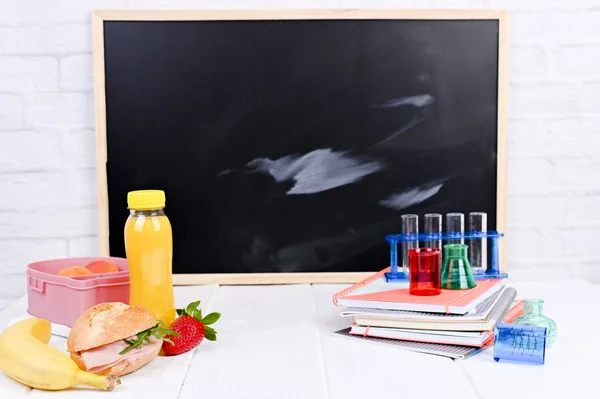 School lunch on the table and a blackboard for a lesson. Childre — Stock Photo, Image