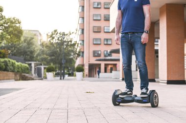 Şehirde hoverboard'da kot pantolon ve spor ayakkabı giymiş bir adam. Ha
