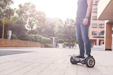 Şehirde hoverboard'da kot pantolon ve spor ayakkabı giymiş bir adam. Ha