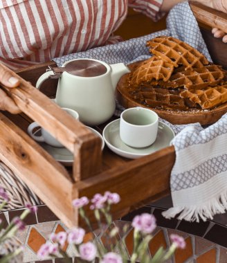 Kadınlar kahvaltıda taze waffle ve çay kupası tutarlar. Anne!