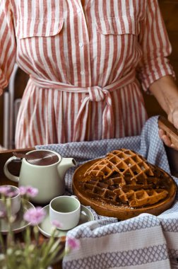 Kadınlar kahvaltıda taze waffle ve çay kupası tutarlar. Anne!