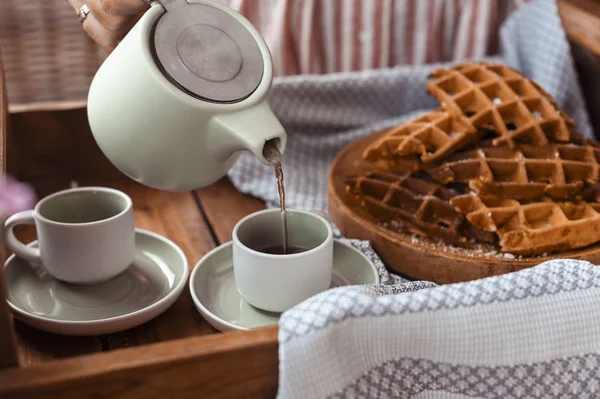 Women holding a kettle and pours tea in a mug. Homemade breakfas — Stock Photo, Image