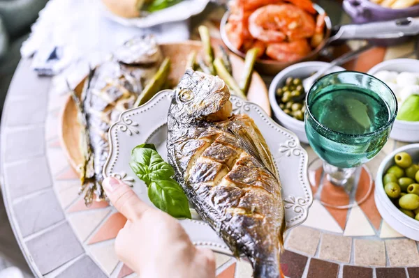 Gebratener Fisch auf einem Teller. Esstisch mit verschiedenen Speisen und Snacks — Stockfoto