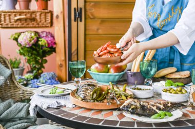 Yemek masasında oturan elinde bir bardak olan mutlu kız. Birçok farklı yiyecek. Servis masası. Rahat ev.