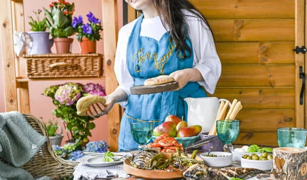 Elinde ekmek olan mavi önlüklü bir kız, akşam yemeğinin yanında. 