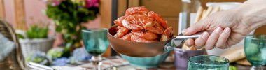 Kadının eli karides tutuyor. Farklı yemek ile yemek masası