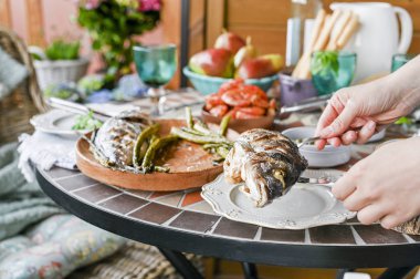 Dişi ellerde bir tabakta kızarmış balık. Differen ile yemek masası