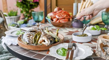 Kadının eli karides tutuyor. Farklı yemek ile yemek masası