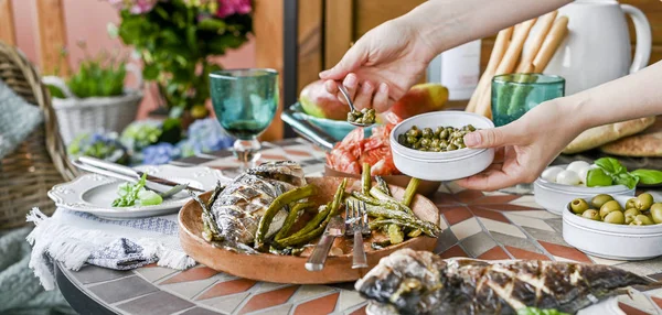 Woman with a plate in her hands. Dining table with different foo — Stock Photo, Image