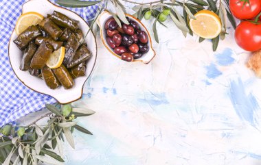 Geleneksel Yunan mutfağı. Üzüm yapraklarına sarılmış pirinç. Limonlu, baharatlı, çeşitli zeytinli ve acı biberli Dolma. Taze dallar ve ev yapımı yiyecekler..