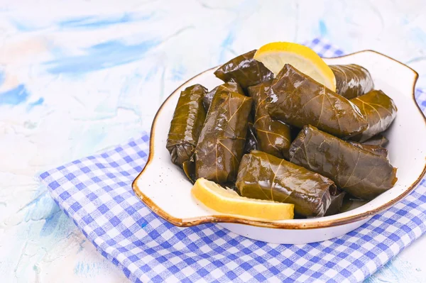 Traditional greek cuisine. Wrapped rice in grape leaves. Dolma with lemon and spices. Home cooked food. Olive branches and various spicy appetizers.
