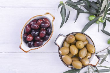 Geleneksel mezeler, Yunan mutfağından zeytinler. Beyaz ahşap arka plan. Yukarıdan bak. Taze zeytin dalları. Boşluğu kopyala.