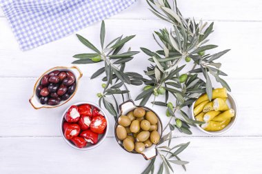 Geleneksel mezeler, Yunan mutfağından zeytinler. Beyaz ahşap arka plan. Yukarıdan bak. Taze zeytin dalları. Boşluğu kopyala.