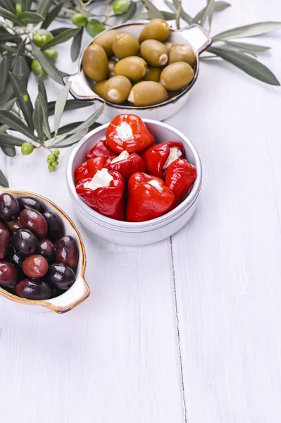 Traditionelle Vorspeisen, Oliven aus der griechischen Küche. Weißer Holz-Hintergrund. Blick von oben. Frische Olivenzweige. Kopierraum. — Stockfoto