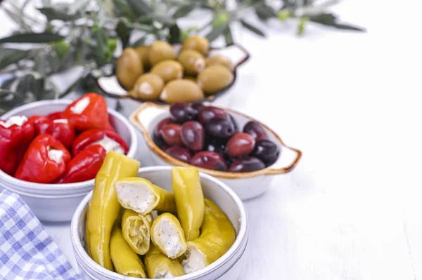 Traditionelle Vorspeisen, grüne und rote Oliven aus der griechischen Küche. Frische Olivenzweige. Kopierraum. Blau karierte Tischdecke. — Stockfoto