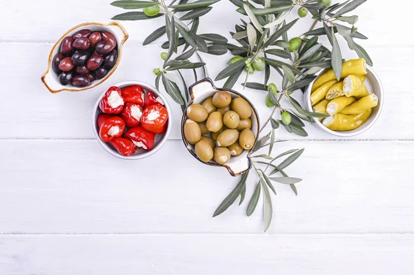 Geleneksel mezeler, Yunan mutfağından zeytinler. Beyaz ahşap arka plan. Yukarıdan bak. Taze zeytin dalları. Boşluğu kopyala.
