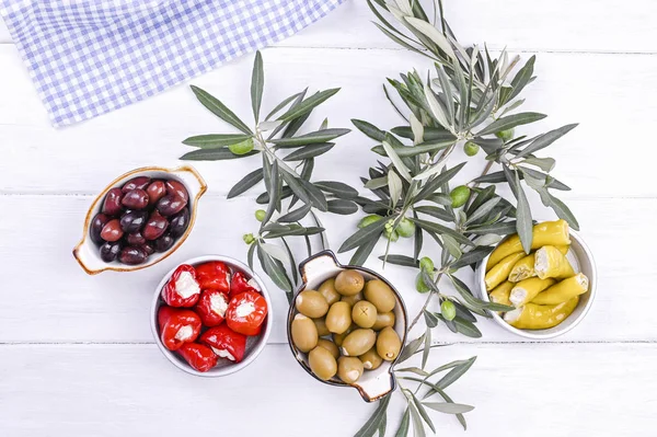 Geleneksel mezeler, Yunan mutfağından zeytinler. Beyaz ahşap arka plan. Yukarıdan bak. Taze zeytin dalları. Boşluğu kopyala.