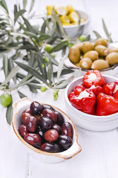 Geleneksel mezeler, Yunan mutfağından zeytinler. Beyaz ahşap arka plan. Yukarıdan bak. Taze zeytin dalları. Boşluğu kopyala.