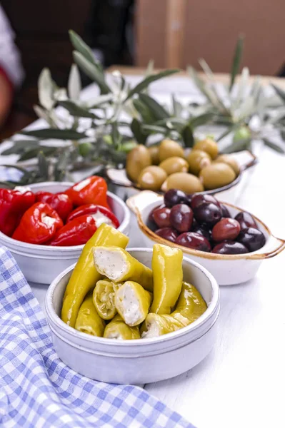 Traditionelle Vorspeisen, grüne und rote Oliven aus der griechischen Küche. Frische Olivenzweige. Kopierraum. Blau karierte Tischdecke. — Stockfoto