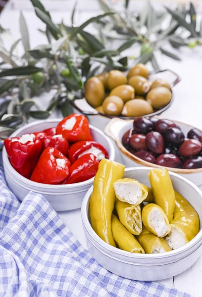 Traditionelle Vorspeisen, grüne und rote Oliven aus der griechischen Küche. Frische Olivenzweige. Kopierraum. Blau karierte Tischdecke. — Stockfoto