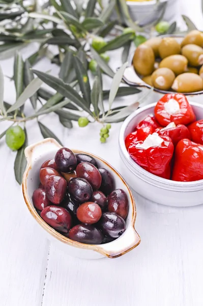 Geleneksel mezeler, Yunan mutfağından zeytinler. Beyaz ahşap arka plan. Yukarıdan bak. Taze zeytin dalları. Boşluğu kopyala.