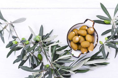 Beyaz ahşap arka planda böğürtlenli taze zeytin dalı. İtalya 'nın geleneksel bitkisi. Metin için boş alan. Düz yatıyordu.