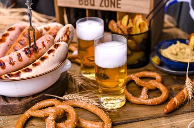 Taze zanaat birası. Izgnde Alman sosisleri var. Bira festivali için geleneksel Alman sosisleri ve pasta brezeli. Ahşap arka plan ve dekor. 