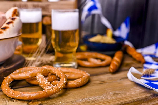 Fresh craft beer. German sausages on the grill. Traditional German sausages and pastry brezel for a beer festival. Wood background and decor.
