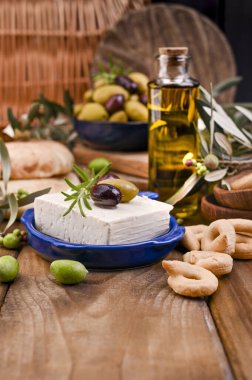 Kekik ve zeytinli Yunan peyniri, seçici odaklı. Ekmek ve taze zeytin dalı, eski ahşap arka planda. Genel Görünüm. 