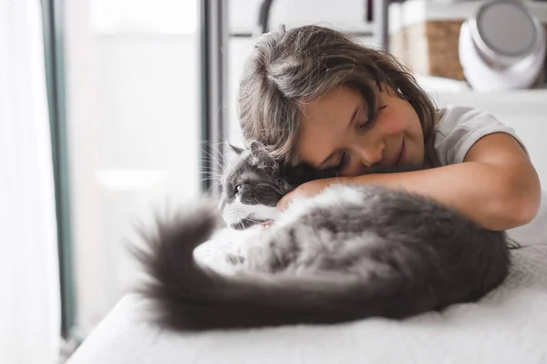 A menina abraça um gato em uma cama em um quarto. A amizade de pessoas e animais. Relações e amor para animais de estimação — Fotografia de Stock
