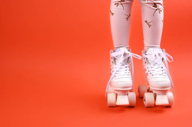 Bir urenburg 'un bacaklarında paten kayıyor. Parlak bir arka planda geçmişe dönük silindirler. Çocukların açık hava sporları konsepti. Metin için boş alan. 