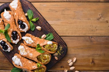 Cannoli Sicilya 'da. Geleneksel İtalyan tatlısı, ricotta ve çeşitli dolgular. Tahta kesme tahtasındaki yemek.