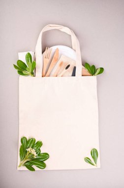  Pamuk eko çanta. Kesme yolu. Tekstil kumaş müşteri paketi şablon oluşturur. Tüketici yeniden kullanılabilir. Taşıyıcı desenli çanta. Tahta diş fırçaları, kağıt tabaklar, yeşil yapraklar. Boşluğu kopyala