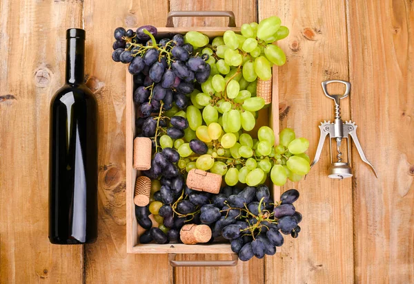 Schachtel mit Trauben, eine Flasche Wein, ein Korkenzieher auf einem hölzernen Hintergrund. Blick von oben. Weinbereitungs- und Erntekonzept in Europa, Italien. Oldtimer-Foto — Stockfoto